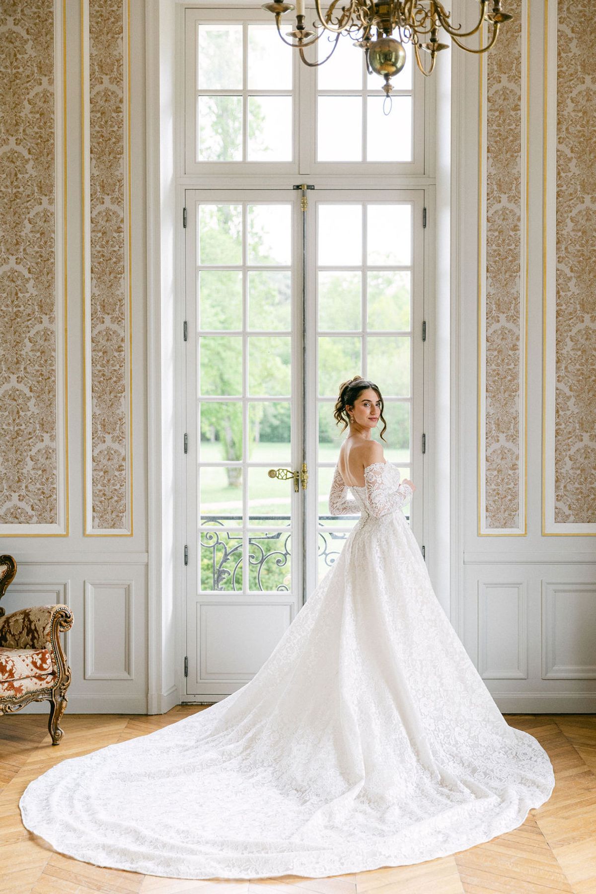 Bride at a tall chateau window with her train spread across the floor