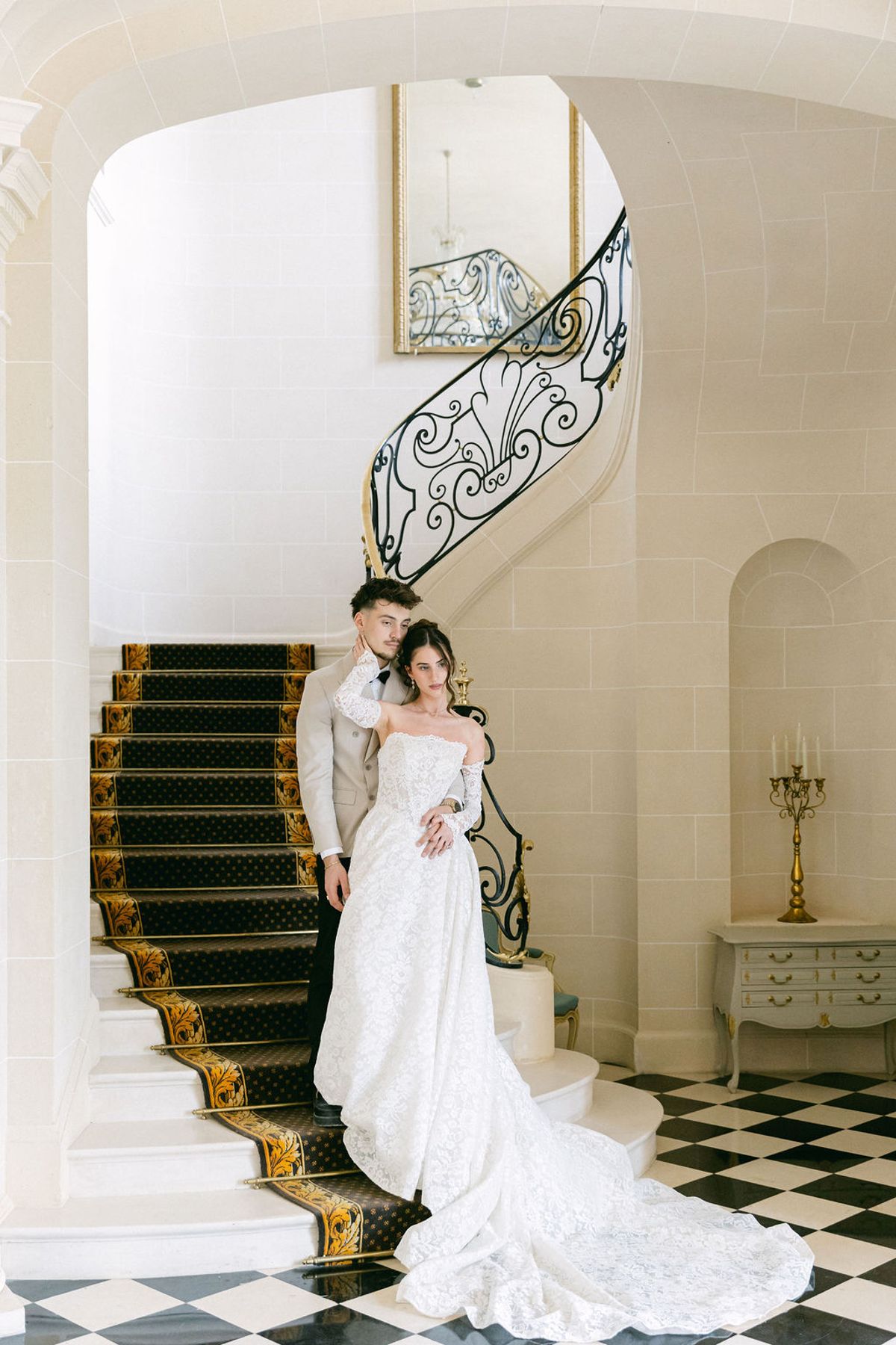 Couple stand together on the curved stone staircase inside the chateau