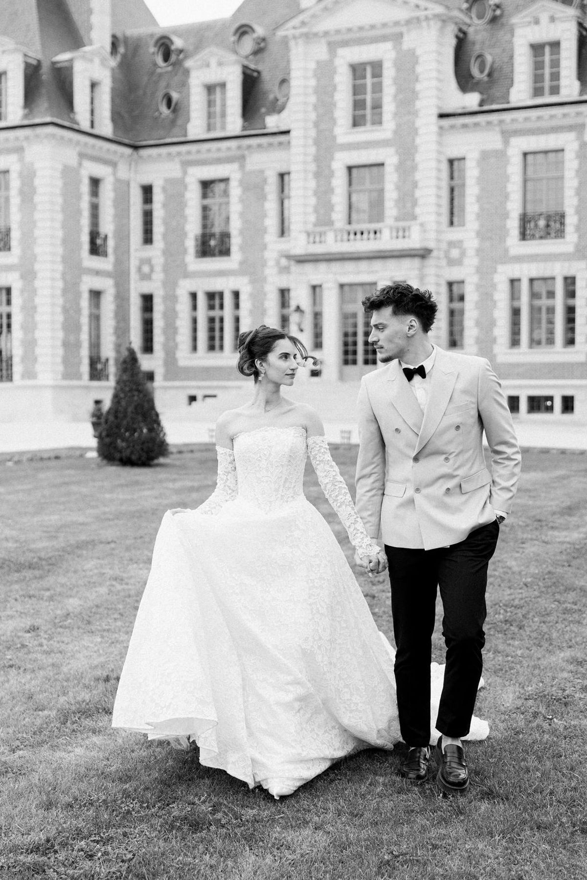 Couple walking together in black and white with the chateau behind