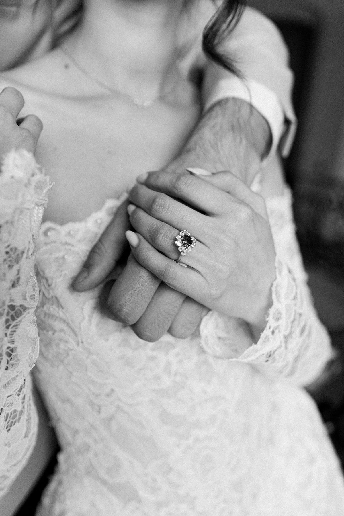 Close-up in black and white of the bride's hand and its ring resting on the groom's