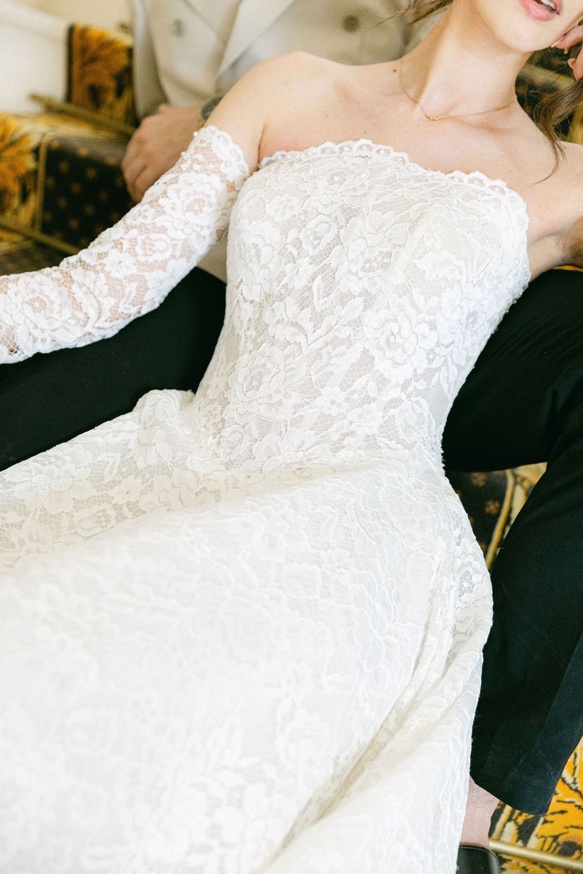 Bride's lace sleeve resting against the groom's black sleeve, close up