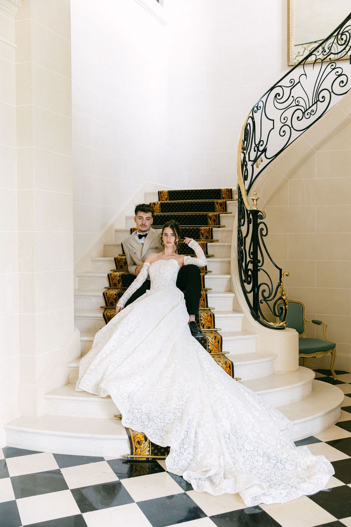 Bride alone on the chateau staircase with her train spilling down the steps