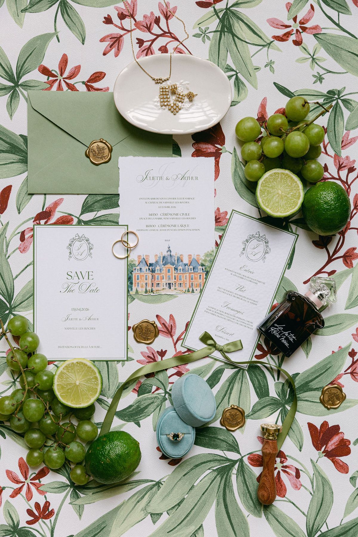 Flat lay of stationery, rings and limes arranged on botanical print fabric