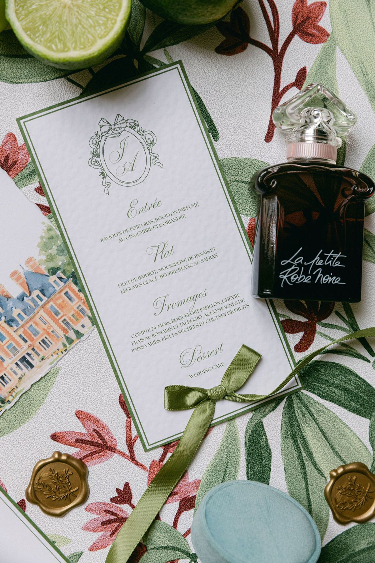 Stationery flat lay with a menu card, wax seals, limes and botanical print fabric