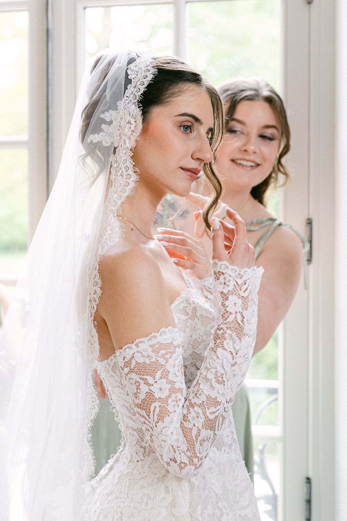 Bride and a bridesmaid together beneath the bride's veil