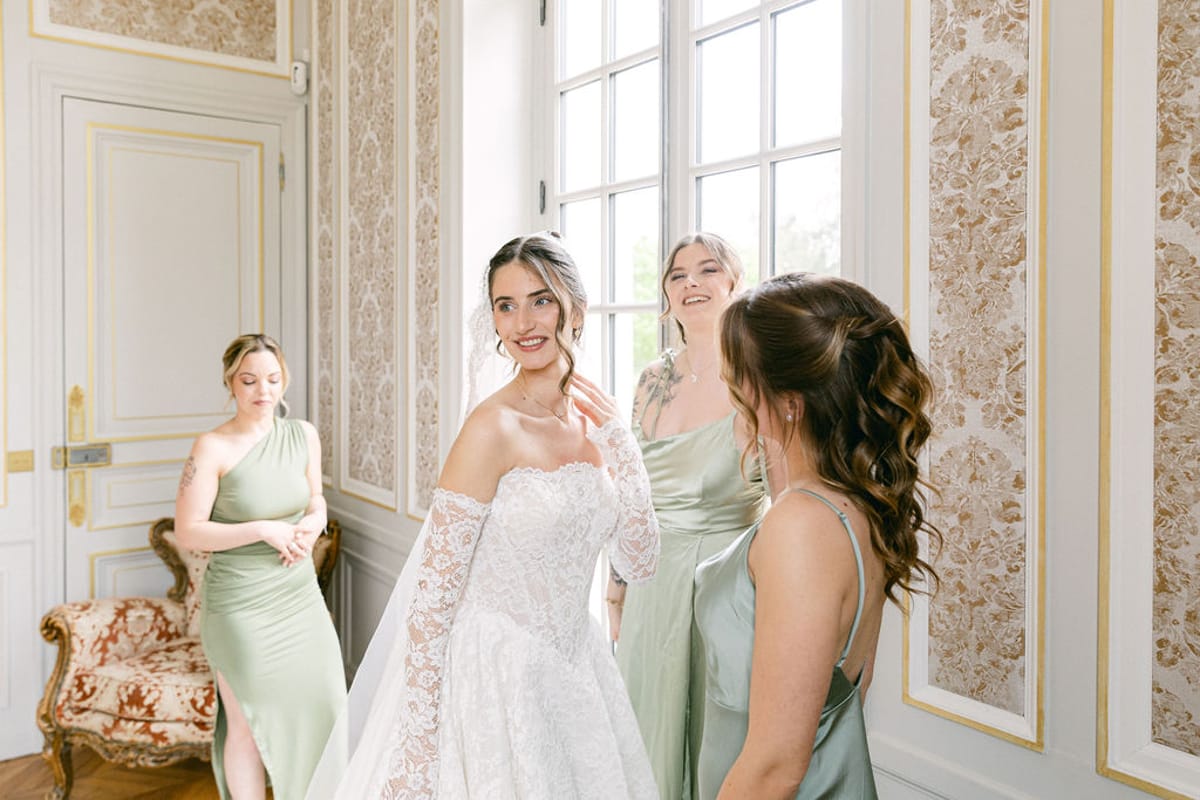 Bride facing the camera in her gown with three bridesmaids gathered around her