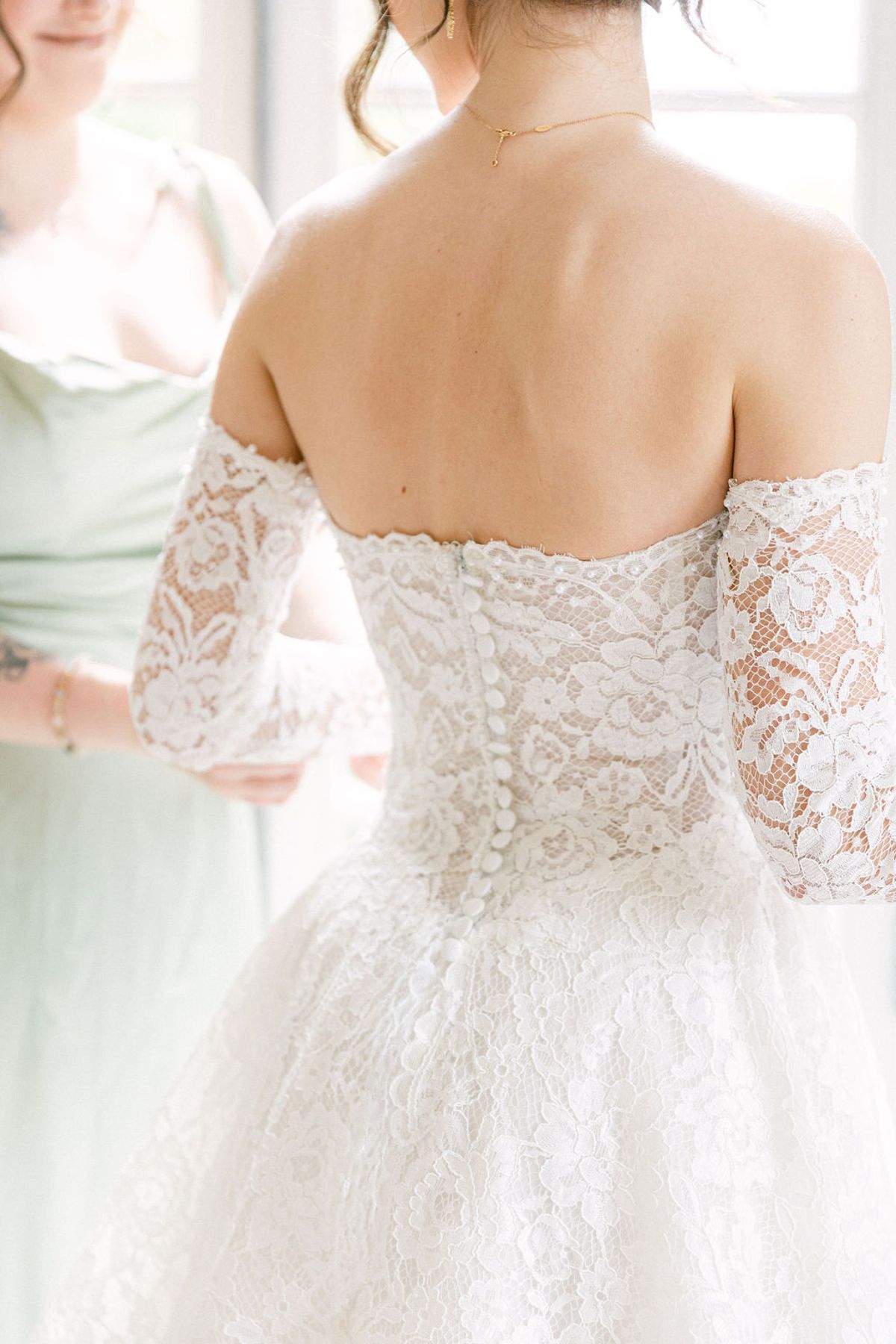 Detail of the bride's lace bodice and bare shoulders as she is dressed