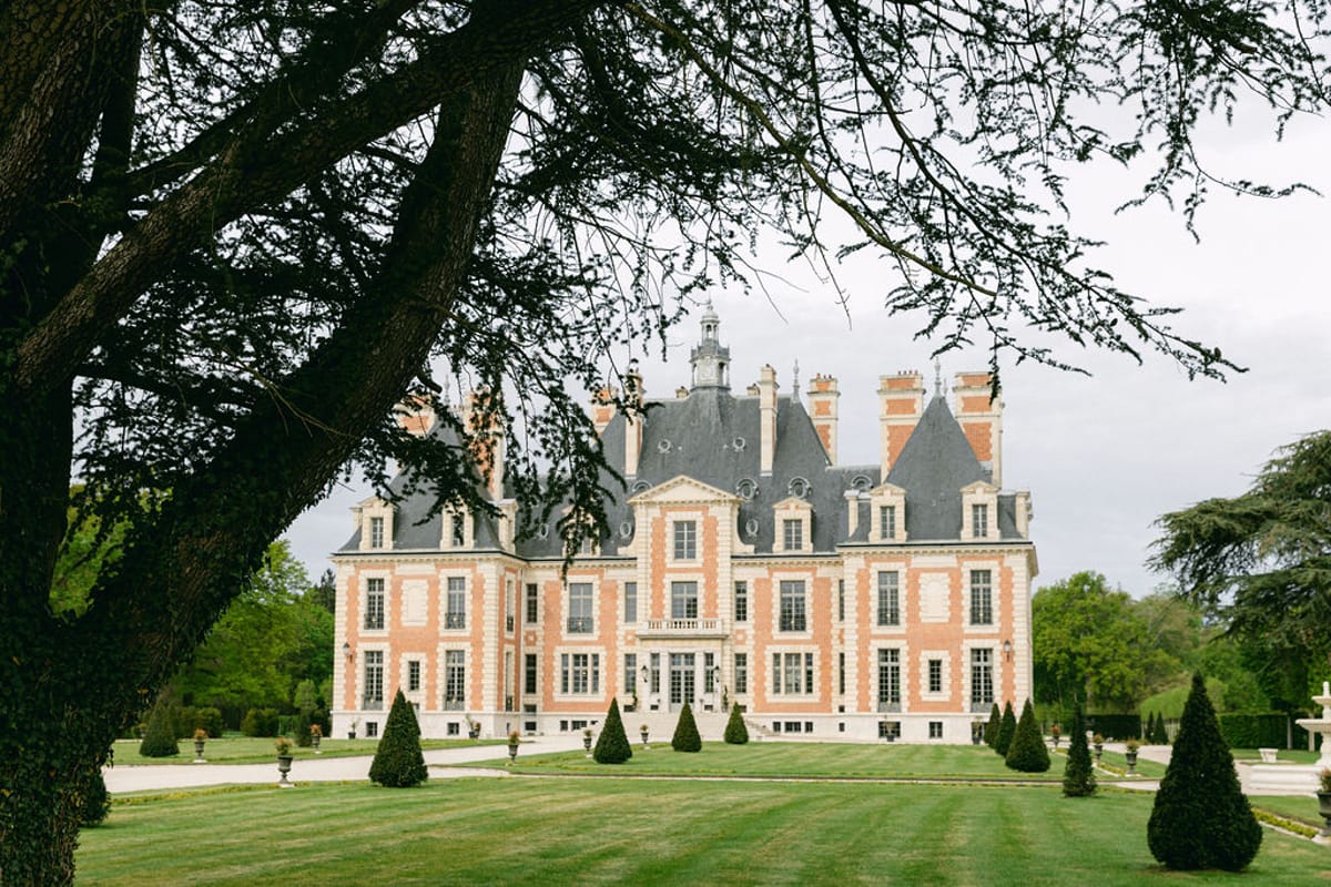 Chateau de Nainville-les-Roches seen across the park through tree branches