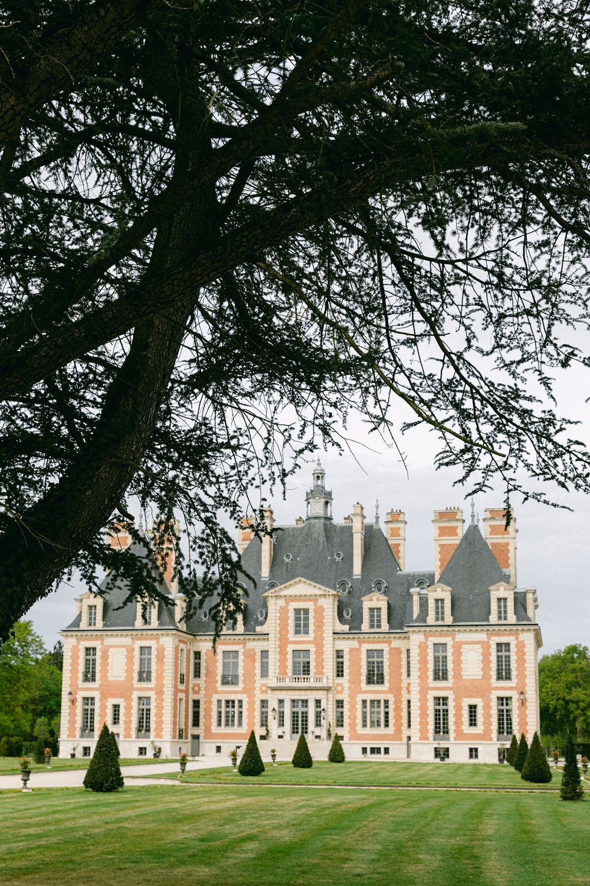 Chateau de Nainville-les-Roches framed by the branches of a park tree