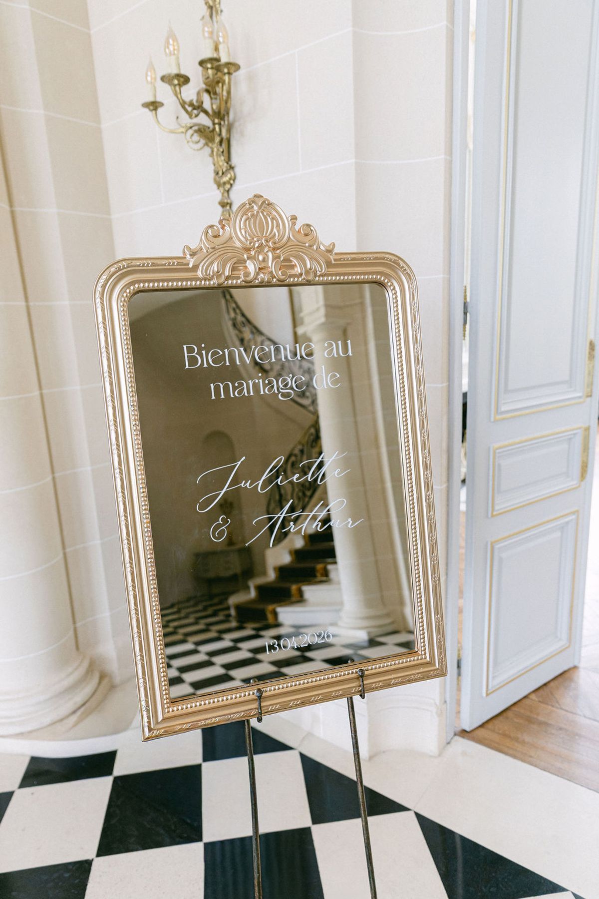 Gilt-framed welcome mirror on a black easel in the chequerboard hall of the chateau