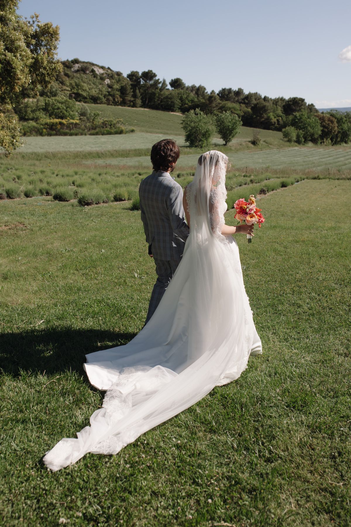 Bride and groom walking hand in hand through a Provence field