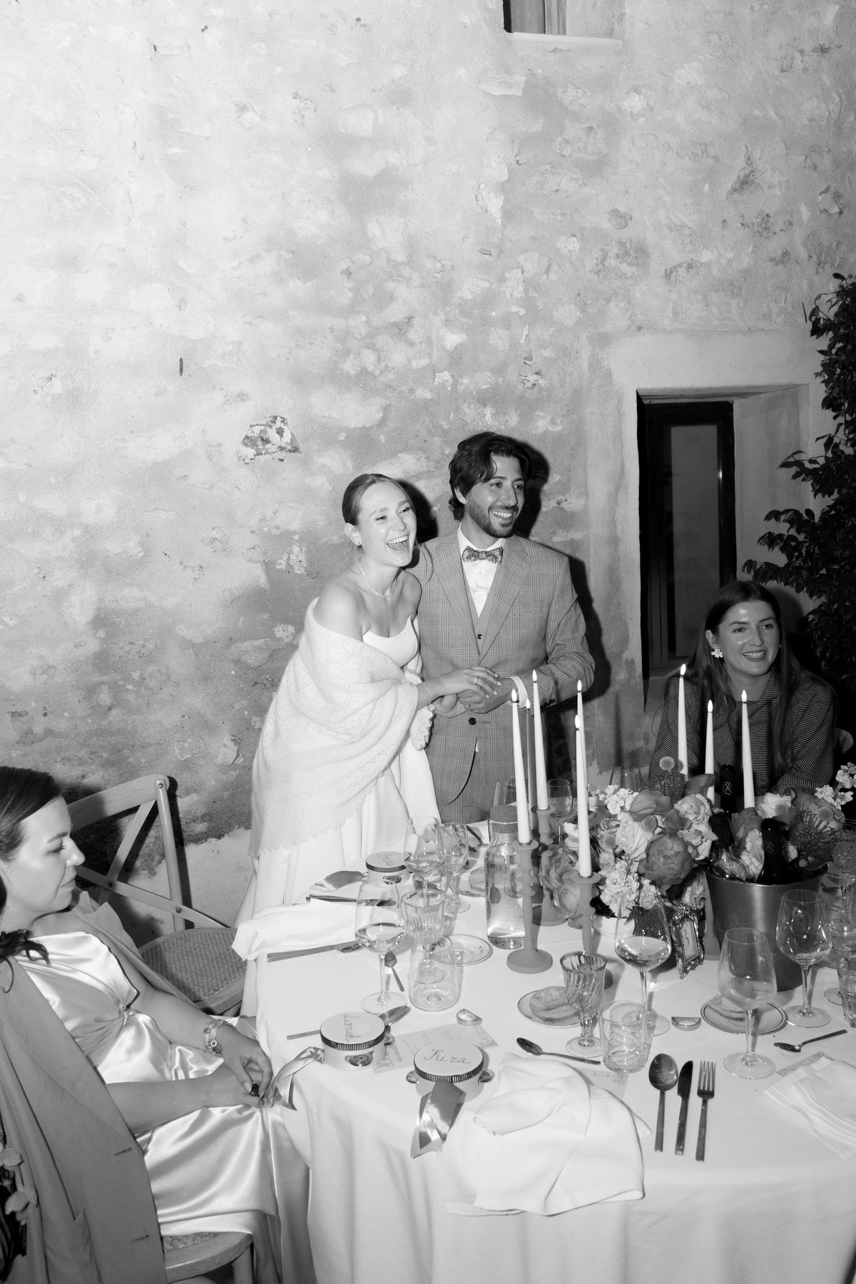 Guests toasting at a candlelit dinner table, black and white