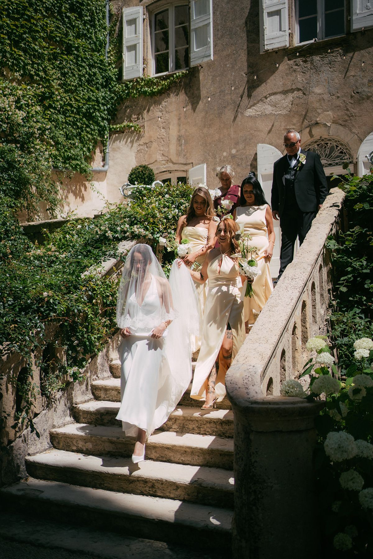 The bride and bridesmaids coming down the stone staircase