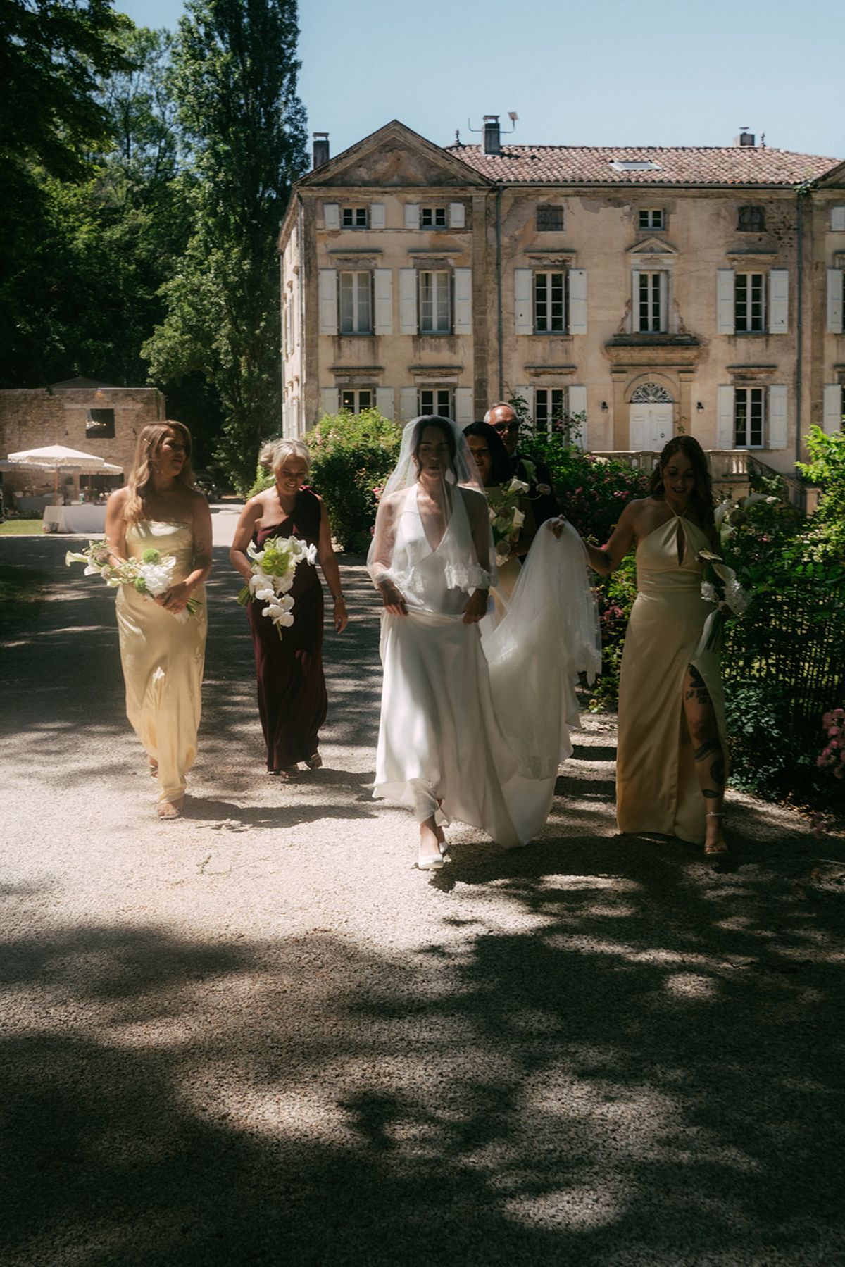 The bride and bridesmaids walking towards the chateau