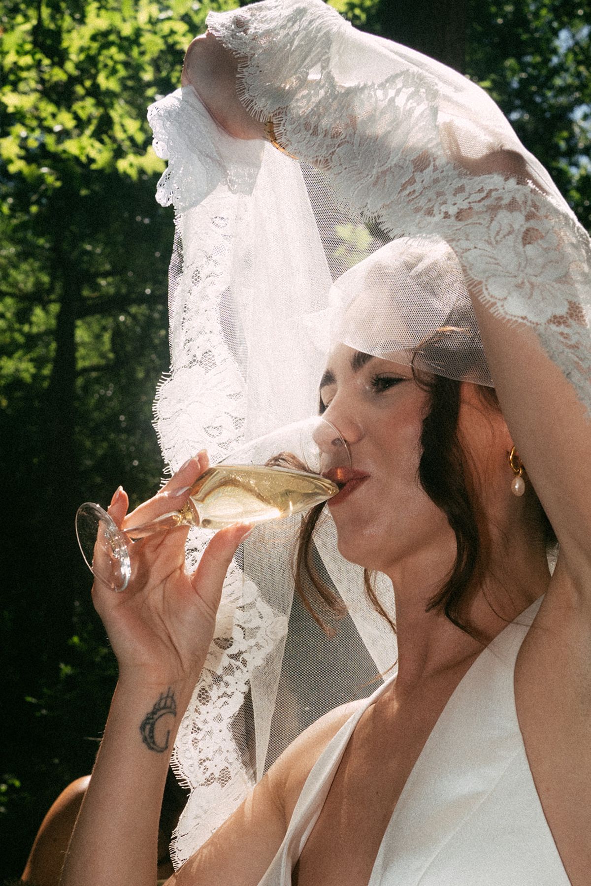 The bride sipping champagne beneath a lace veil