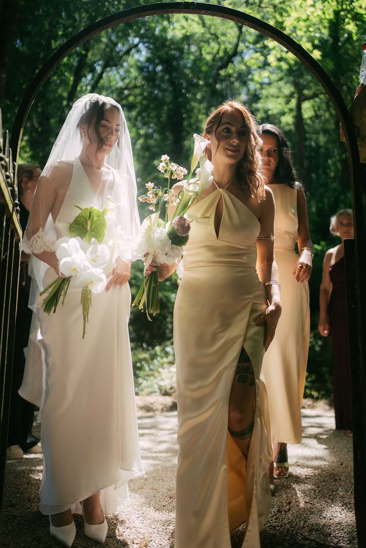 The bride and her bridesmaids walking beneath the arch