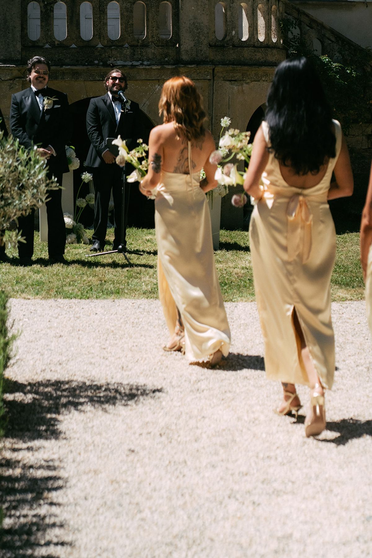 Bridesmaids in gold walking the gravel aisle at Chateau du Pont Bourguet
