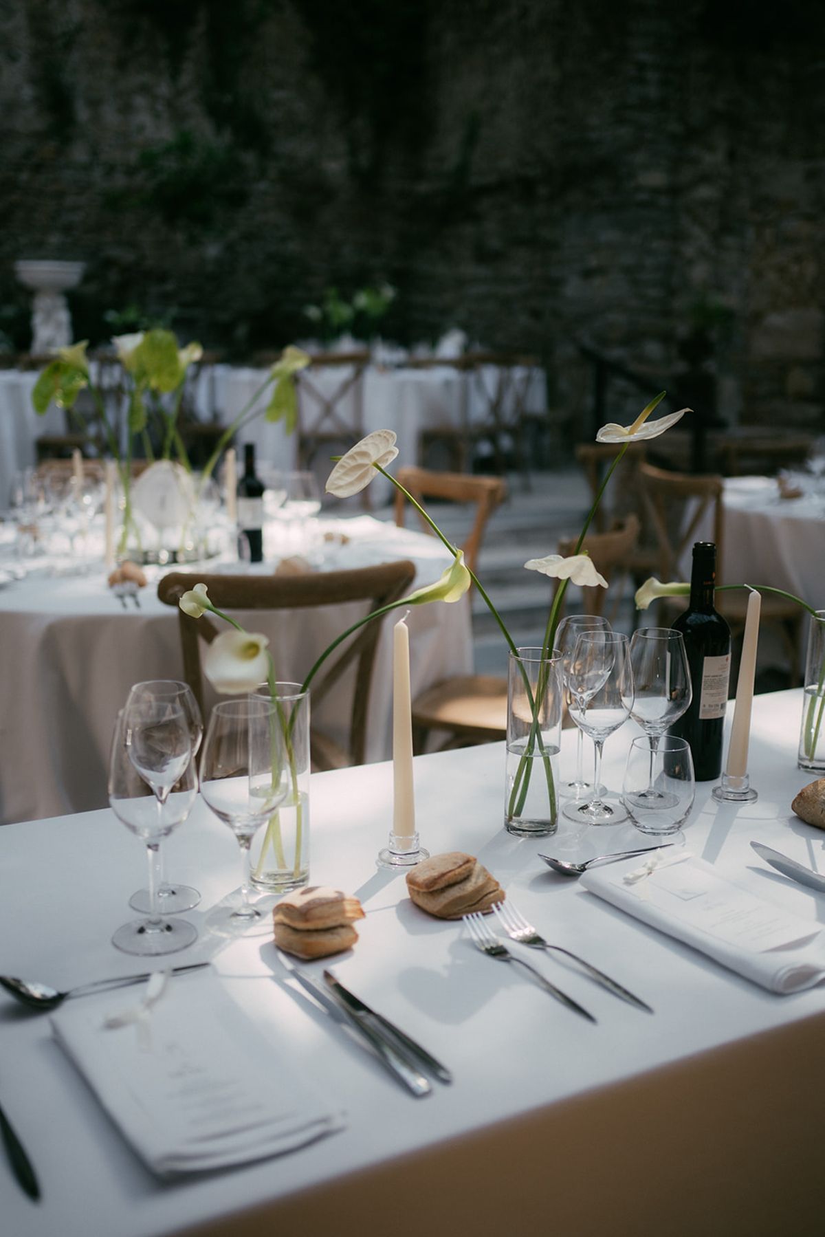 Dinner tables set with candles and calla stems in glass