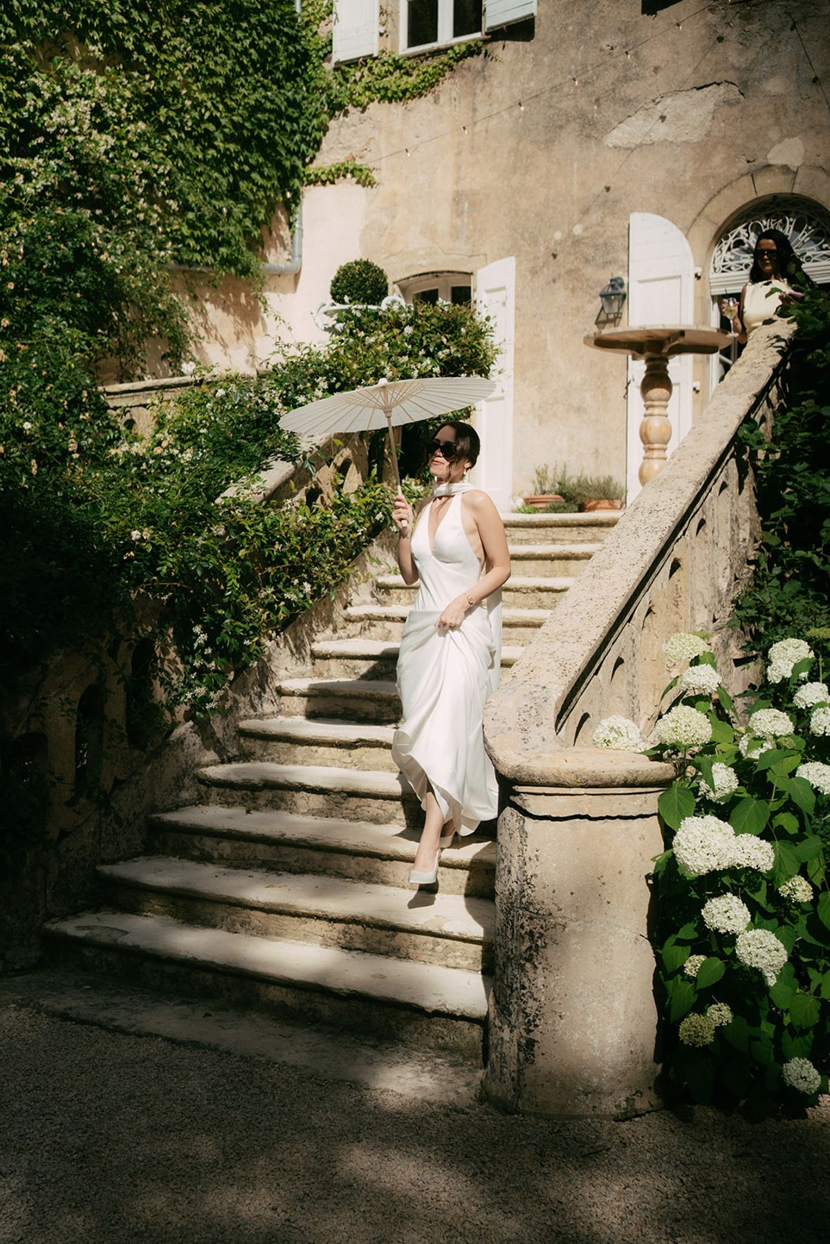 The bride coming down the stone staircase past the hydrangeas