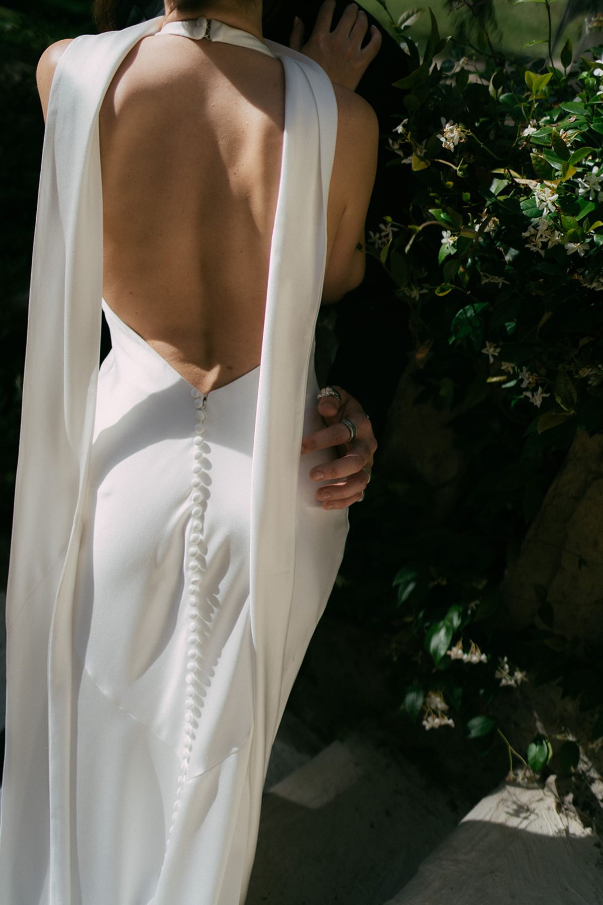The back of the bride's buttoned gown, her veil over one shoulder