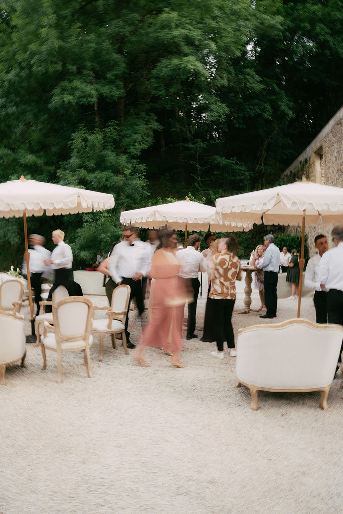 Guests under parasols on the gravel terrace at Chateau du Pont Bourguet