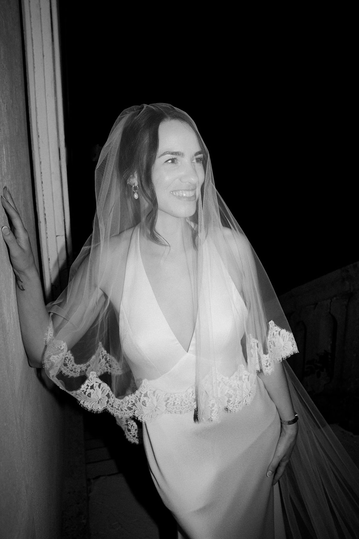 Portrait of the bride in her veil by a window, in black and white