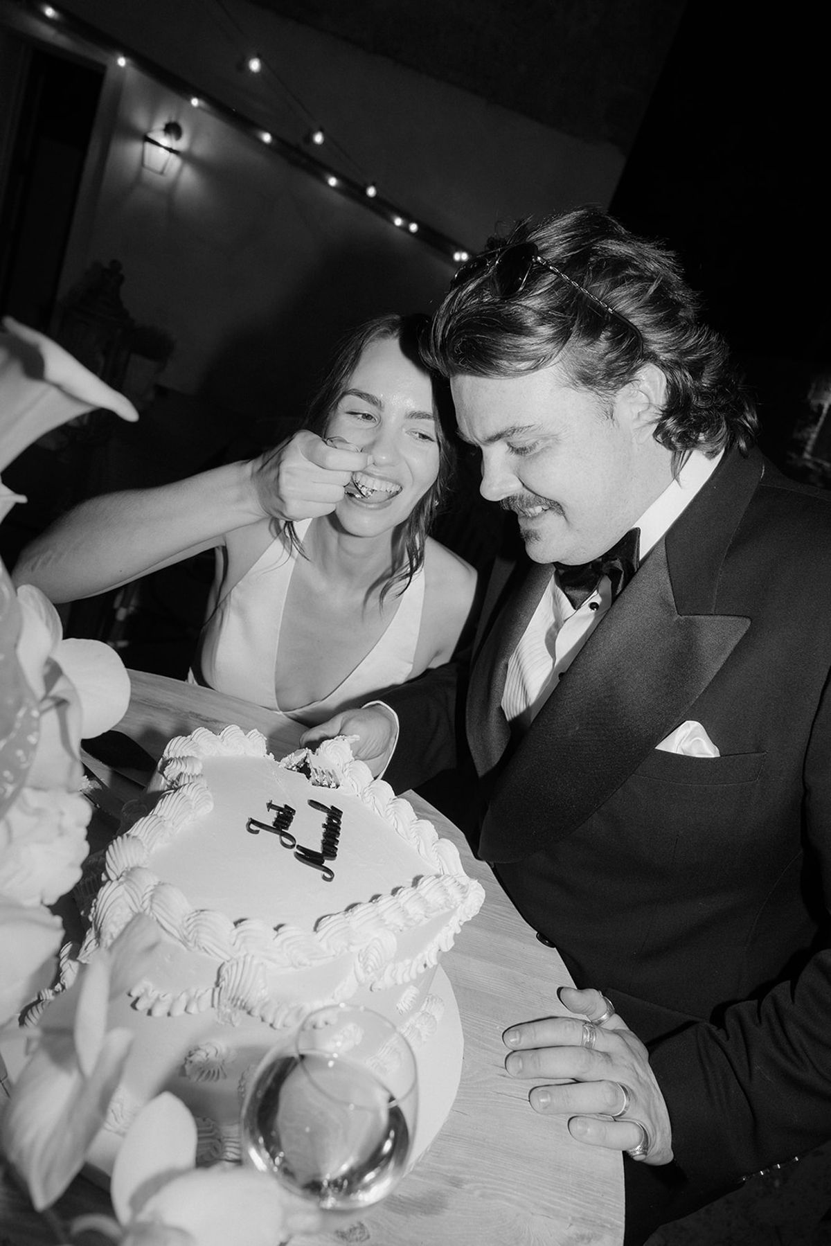 Jasmin and David cutting the cake, photographed in black and white