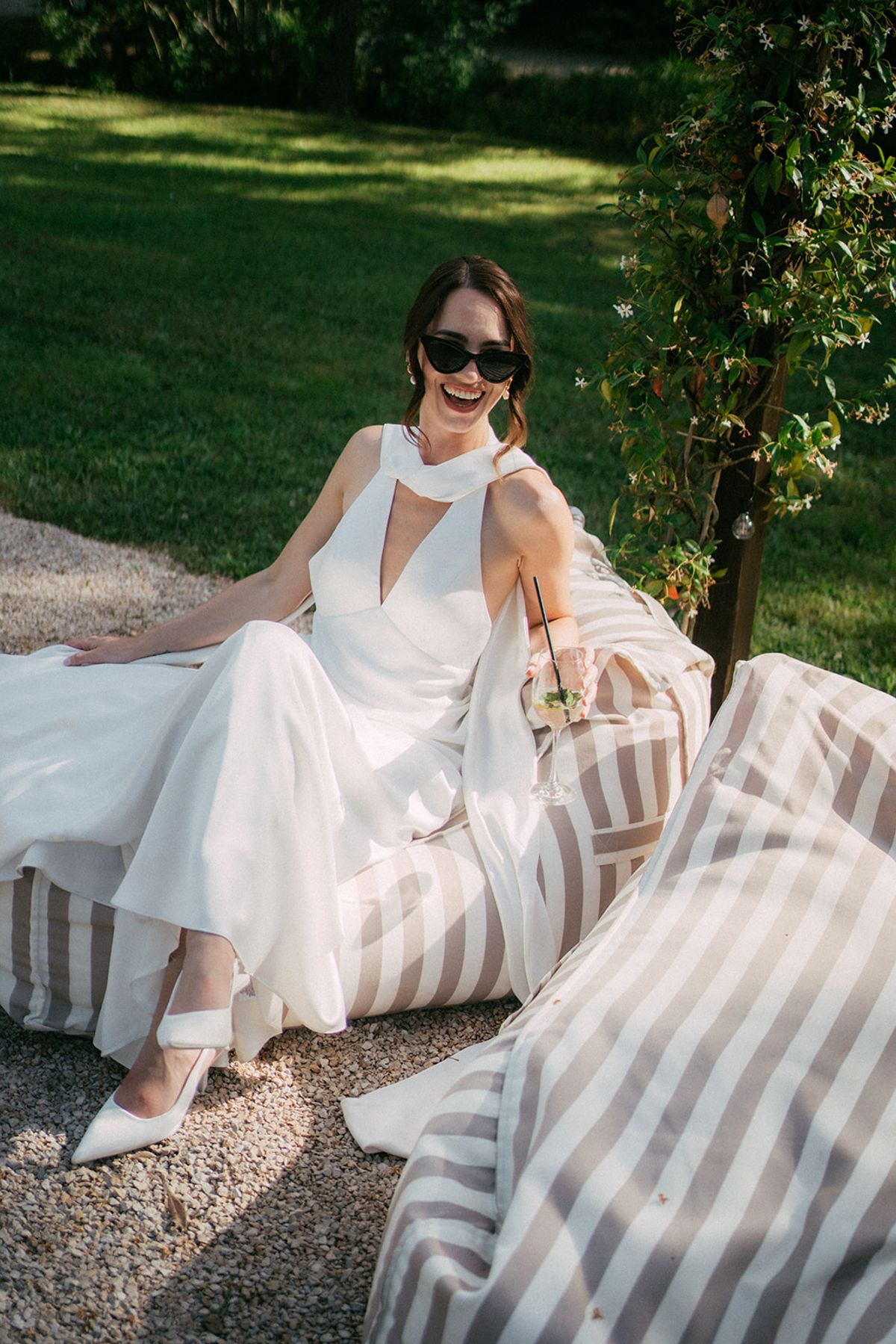 The bride in sunglasses on a striped daybed in the grounds