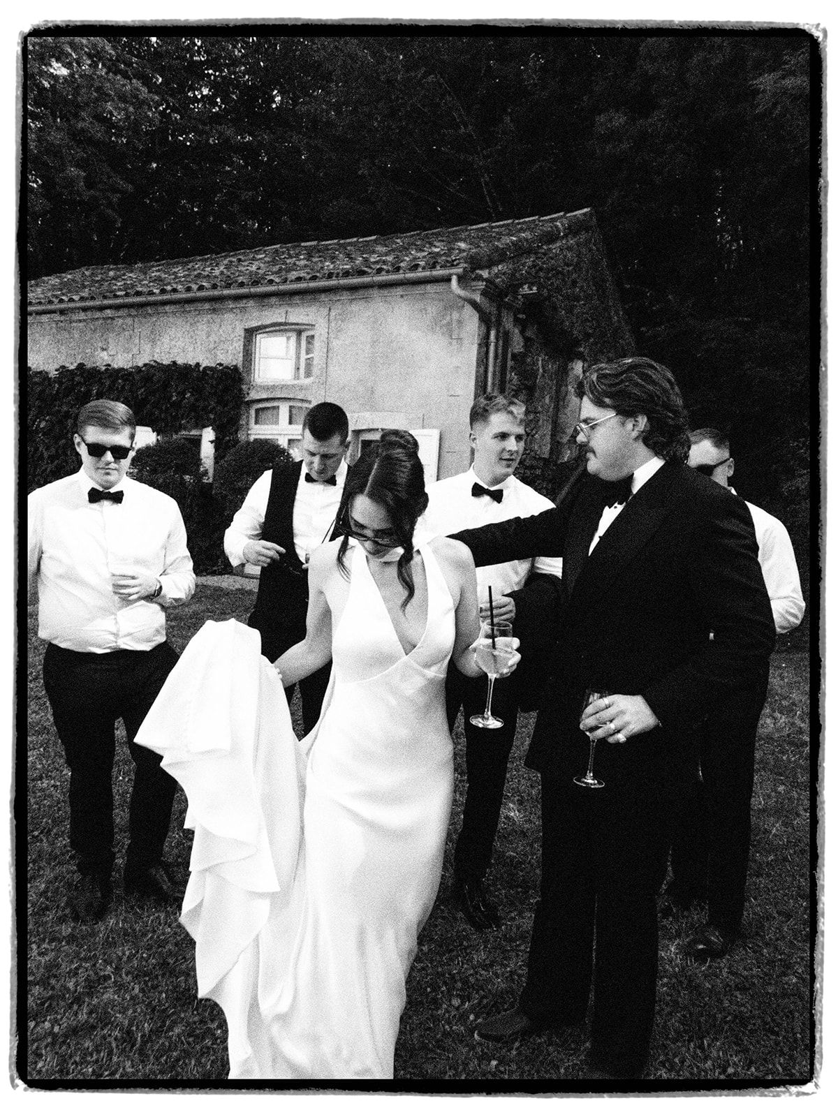 The bride with the groomsmen on the lawn, in black and white