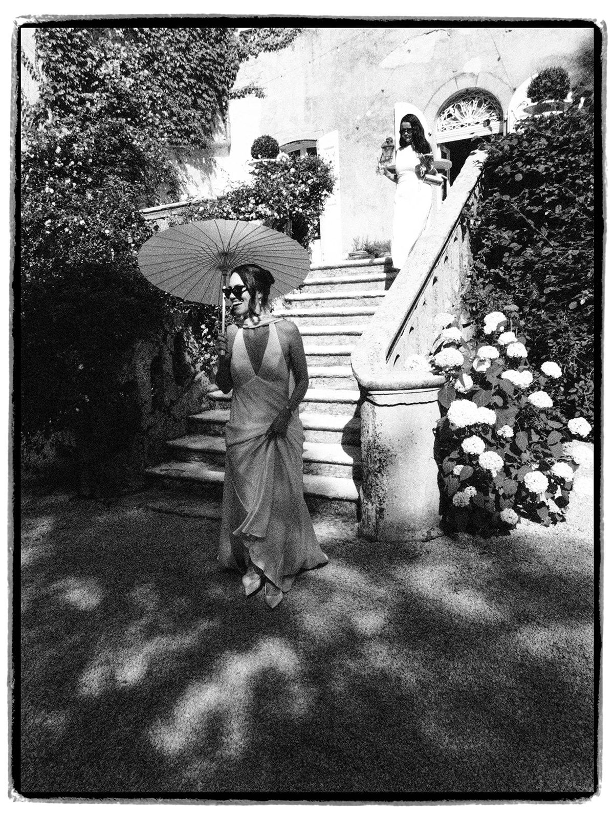 A guest with a parasol on the chateau steps, in black and white
