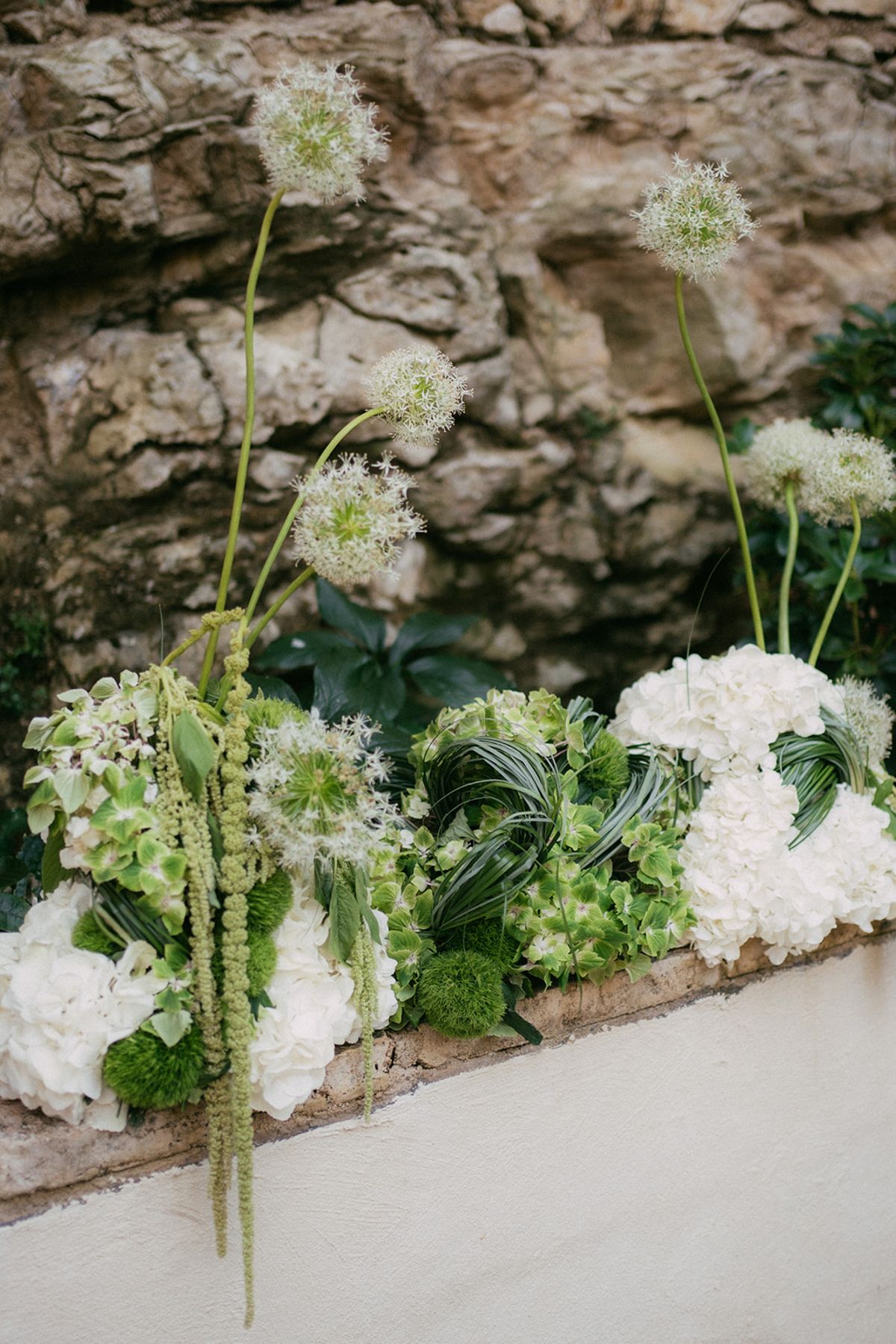 White blooms and greenery arranged along a low stone wall