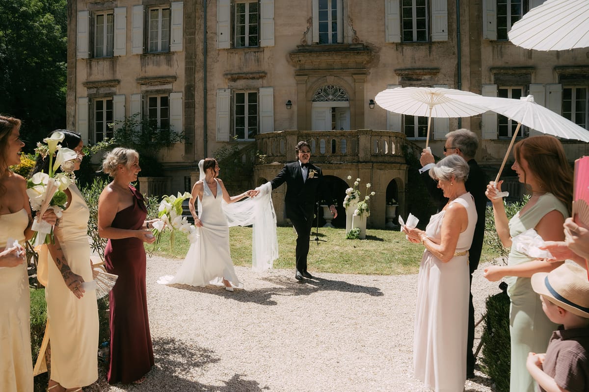 Jasmin and David leaving the ceremony past guests with parasols