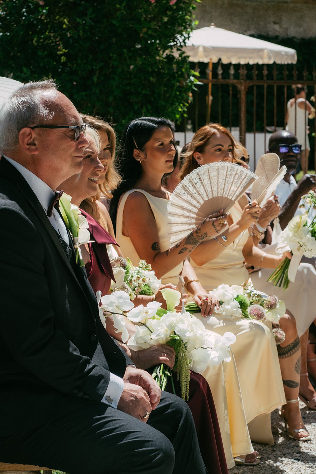 Guests seated with fans in the heat of the ceremony