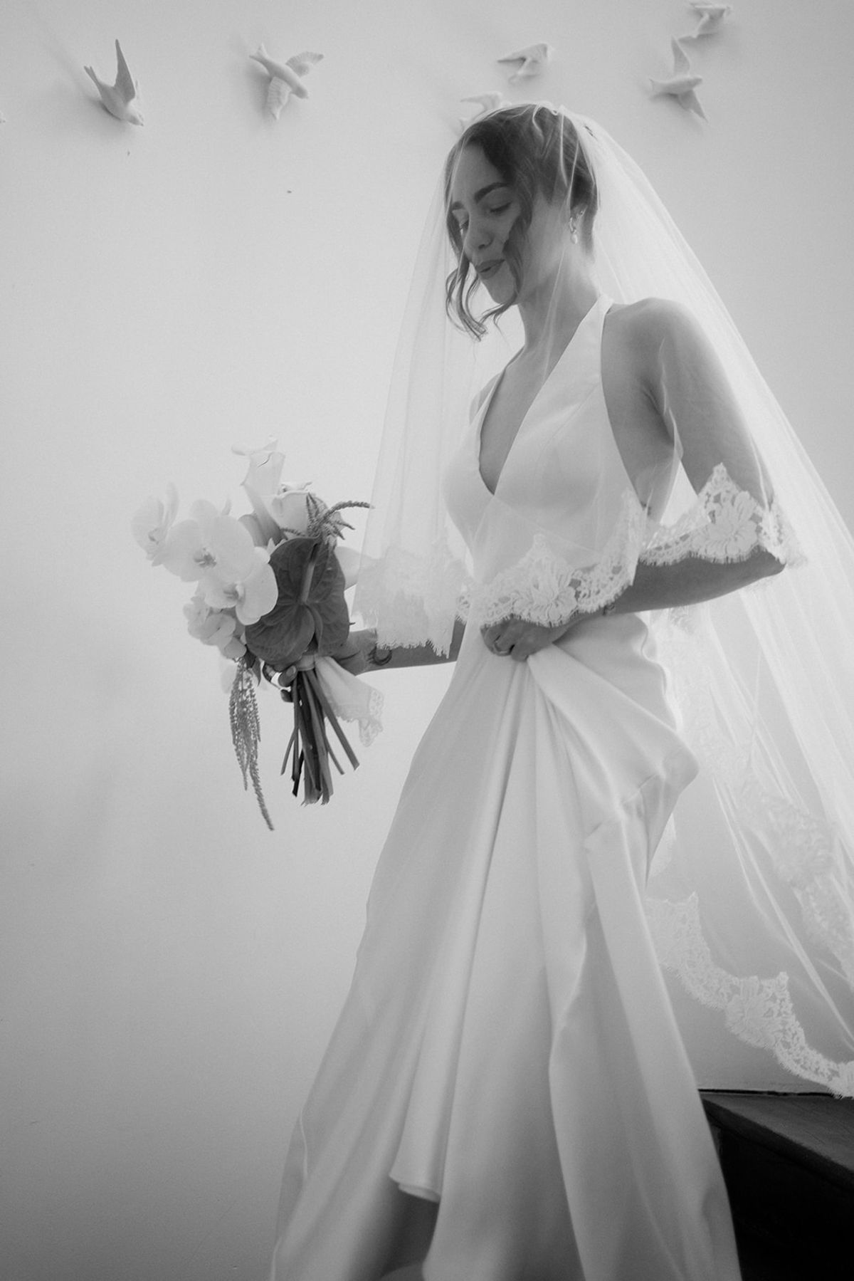 The bride with her bouquet, paper birds on the wall behind her