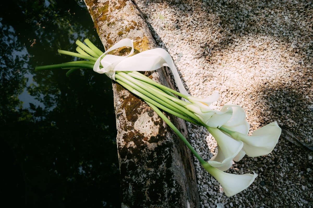 A calla lily bouquet laid on a stone wall at Chateau du Pont Bourguet