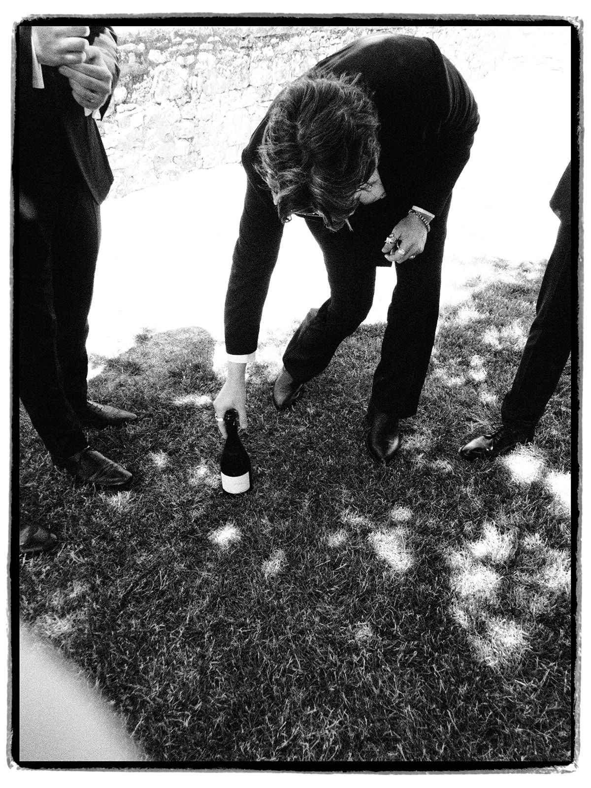 A champagne bottle set down on the grass during a garden game