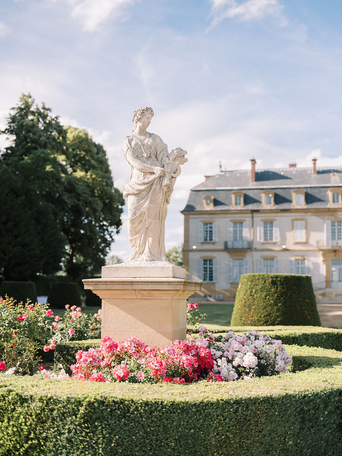 A garden statue among the flowerbeds beside the chateau