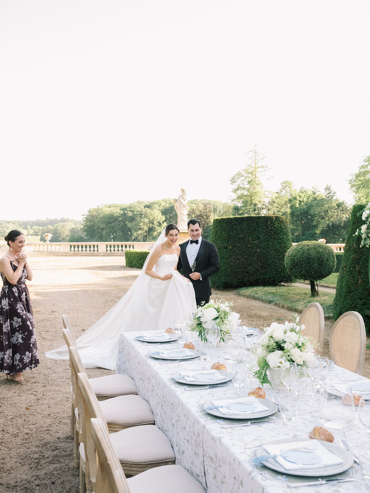 The laid table with Haley and Tyler beyond it in the gardens