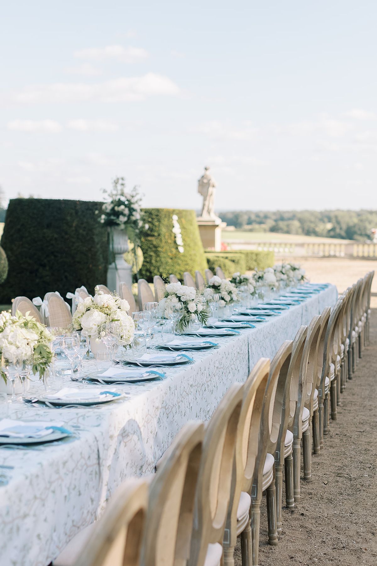 The long table laid with textured linen, candles and white florals