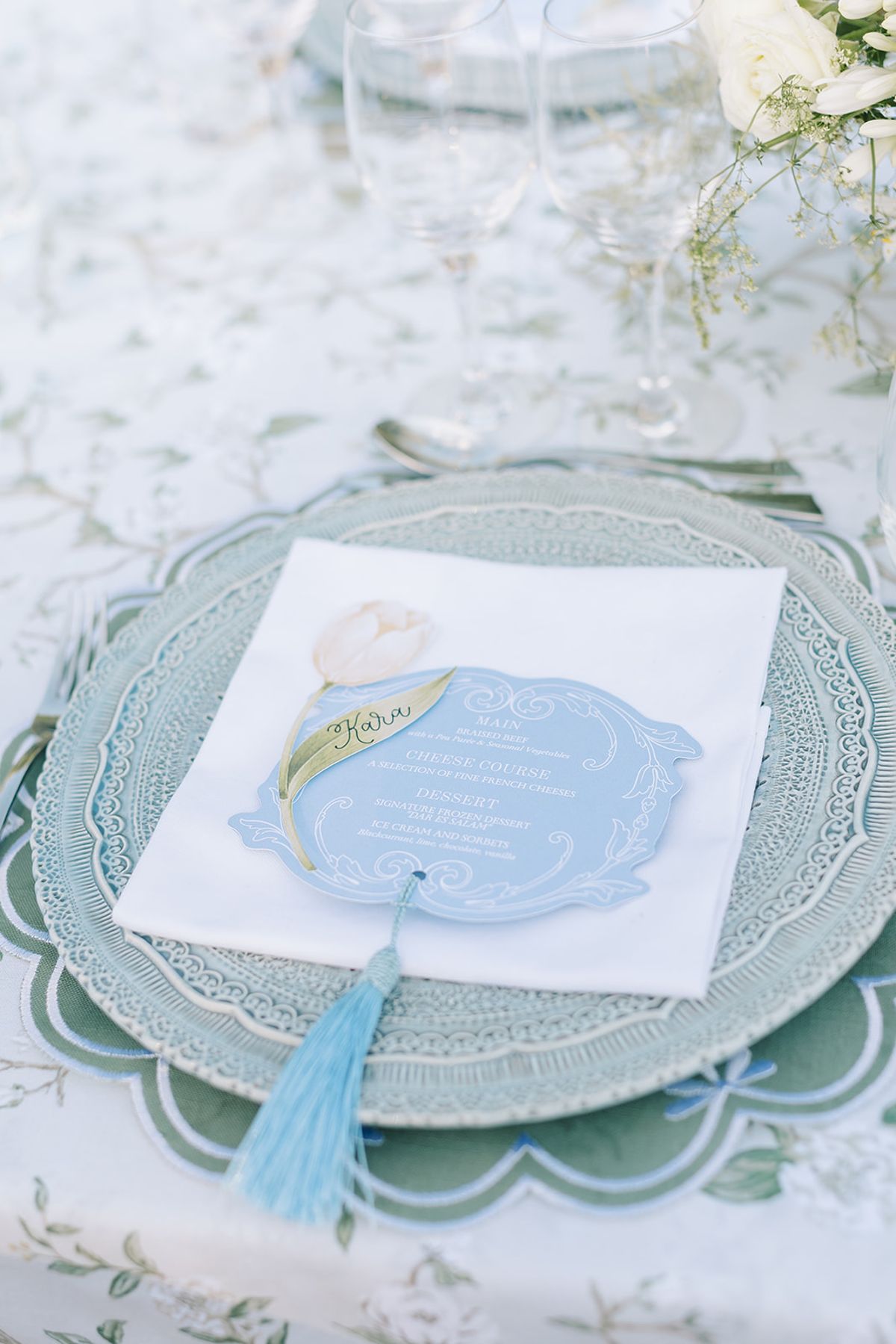 A place setting with scalloped green glass and the blue menu card