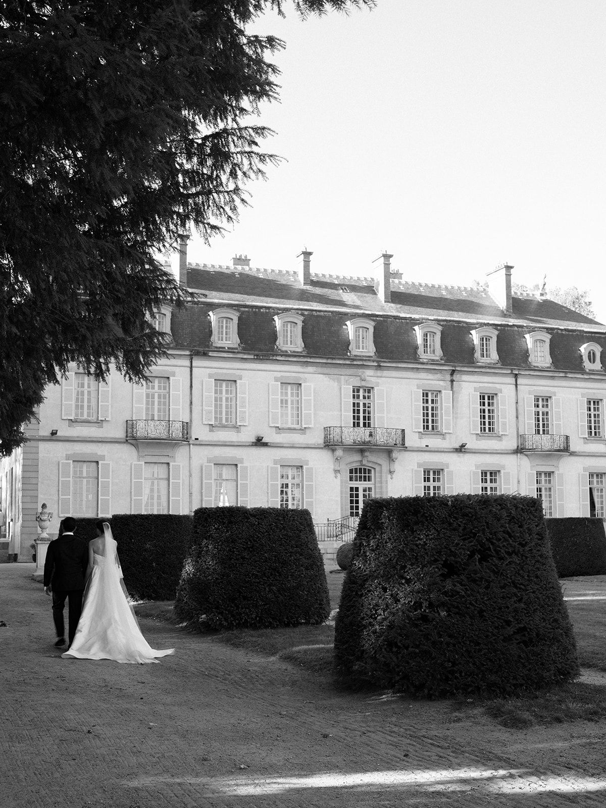 The facade of La Chassagne with the couple small against the topiary