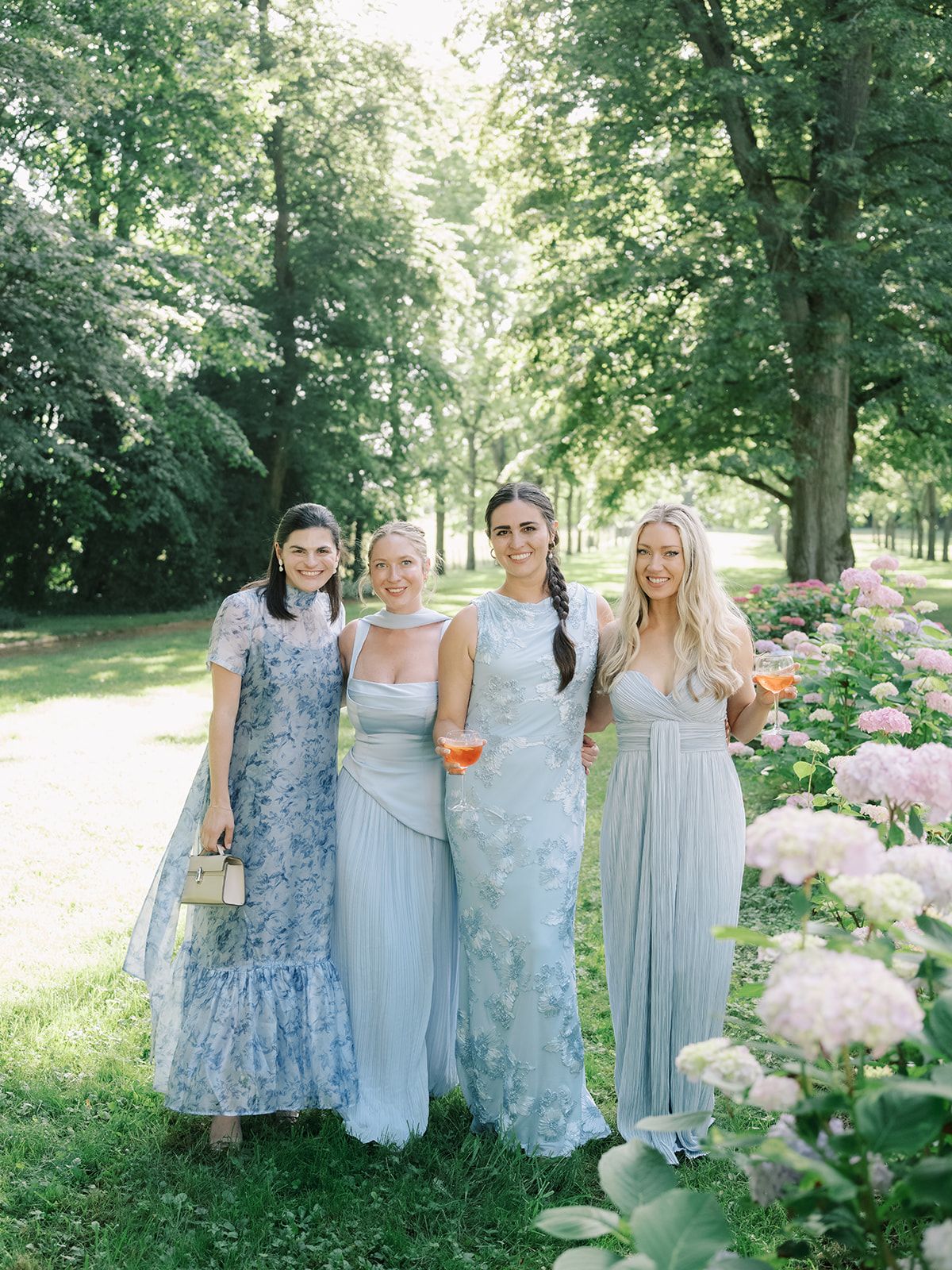 Guests in blue and green gowns beside the hydrangeas