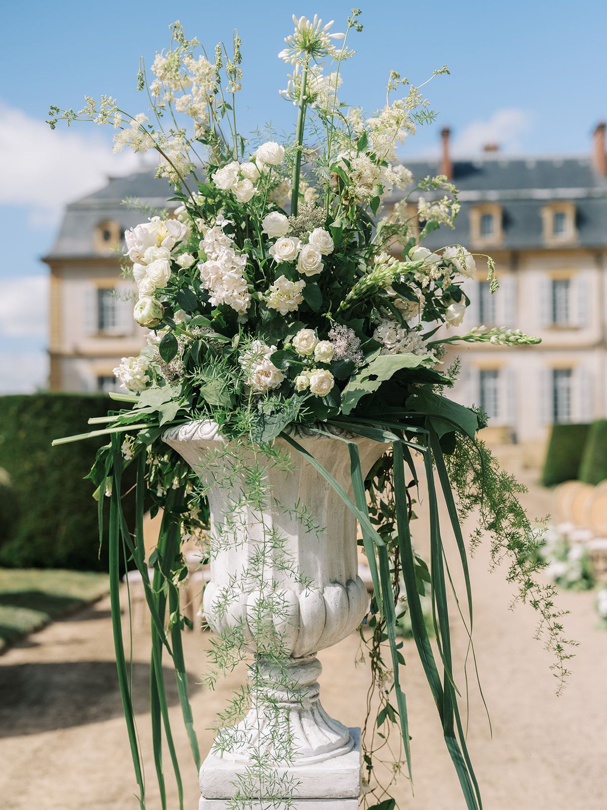A tall urn of white garden flowers and trailing greenery