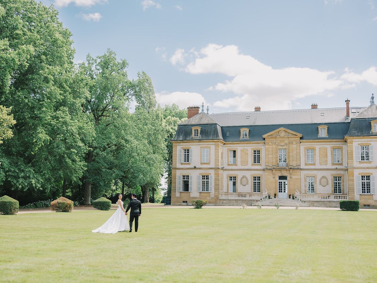 The lawn and facade of La Chassagne with the couple in the distance