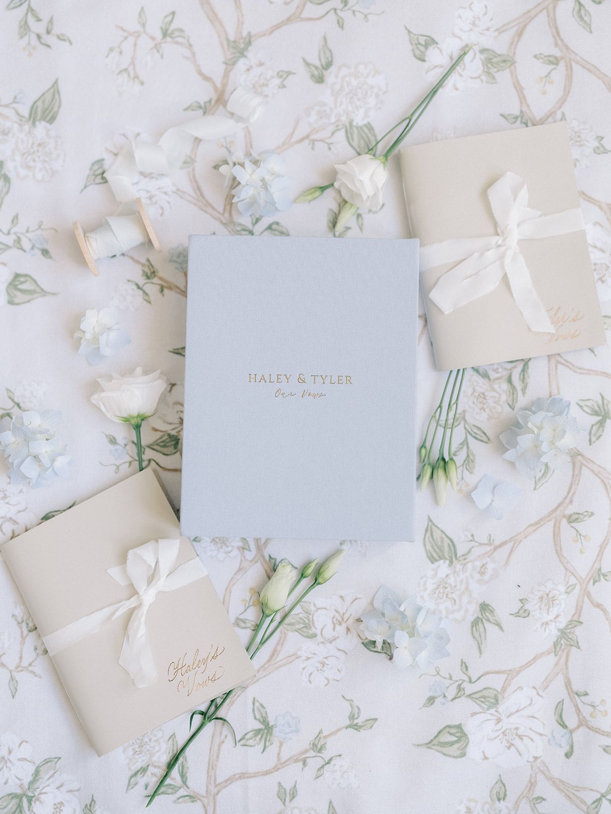The invitation suite laid out with white roses and ribbon