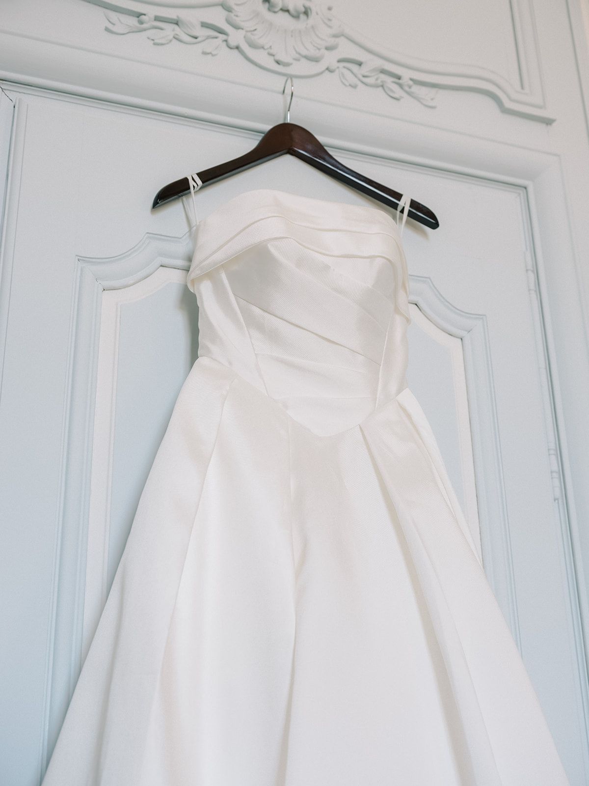 The gown on its hanger against the panelling