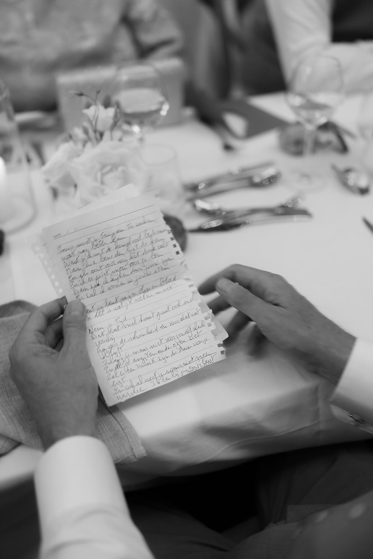 Hands holding a handwritten letter at the dinner table
