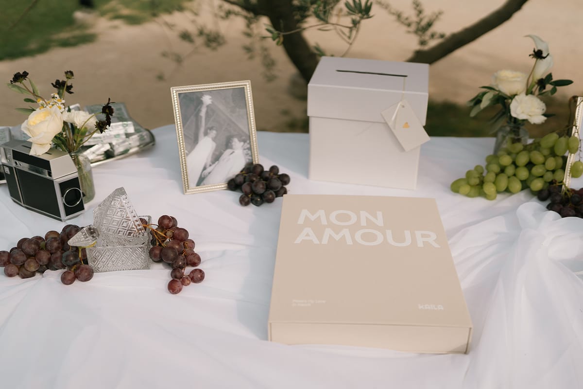 A guest book table with a framed photograph, grapes and a card box