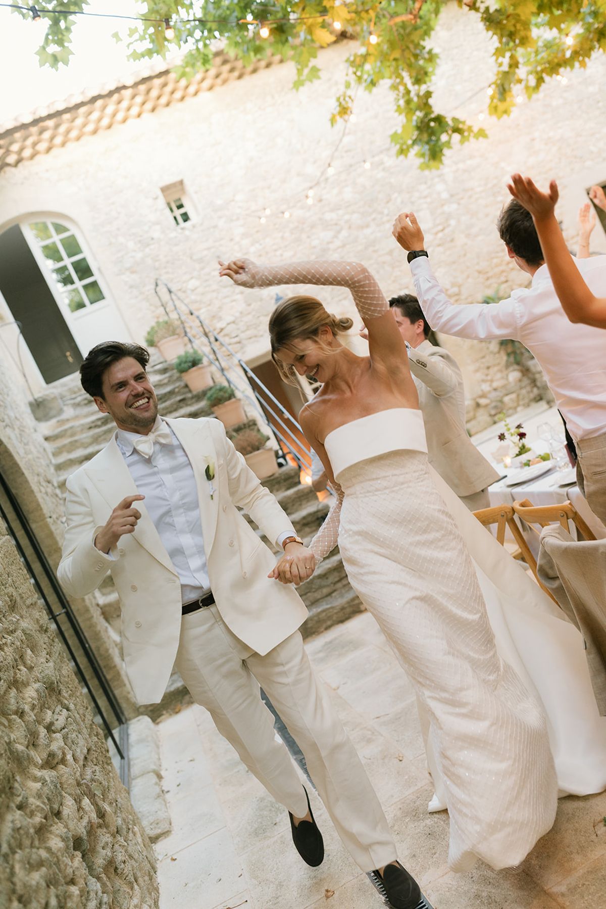 The bride and groom dance into the courtyard for dinner as guests cheer