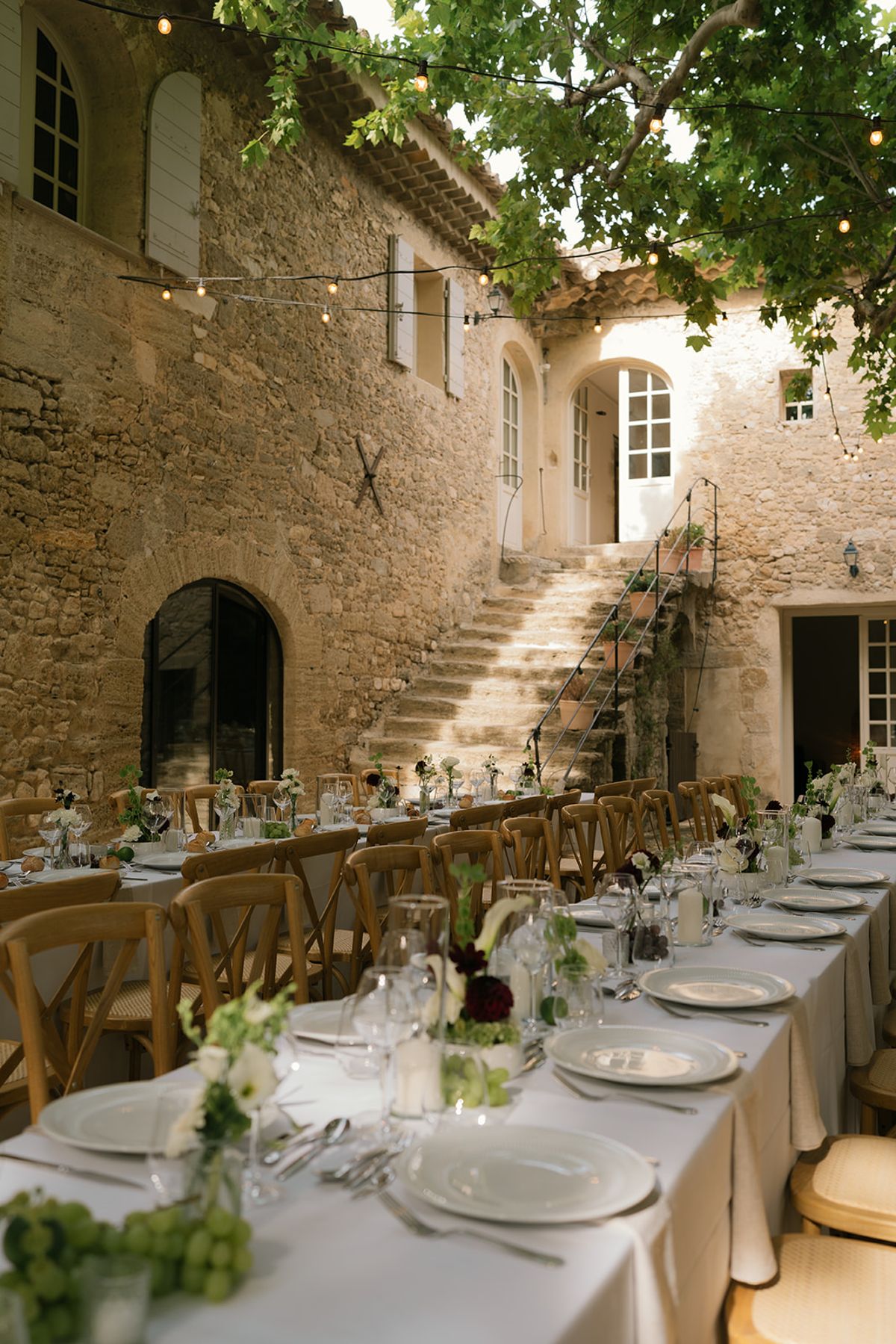 A long dinner table running towards the stone house and its outdoor staircase